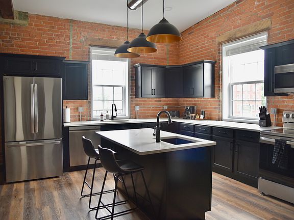 Check out this gorgeous kitchen! The exposed brick and lighting are gorgeous in here. The kitchen features a large kitchen island, an electric stove and oven refrigerator with freezer and water dispenser, microwave and dishwasher.