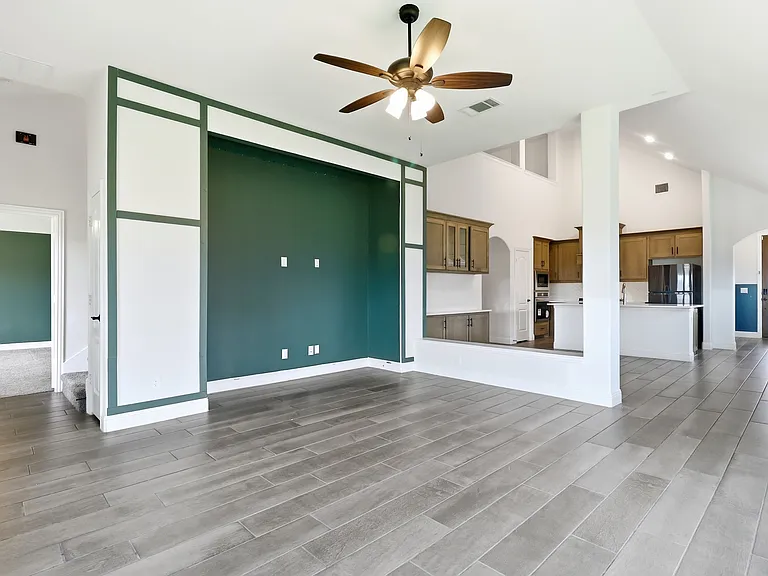 Open-concept living space featuring wood-finish tile flooring and a decorative accent wall
