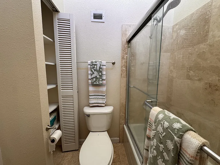 Hallway bathroom with storage space, tub with sliding doors