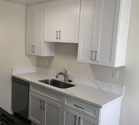 Newly remodeled kitchen with undermount sink and white shaker cabinets and quartz countertop