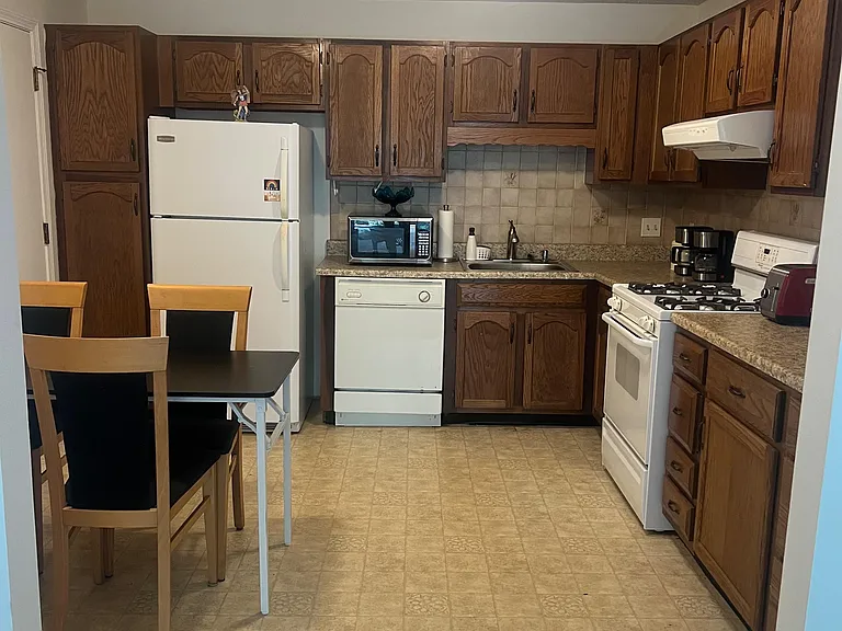 Eat-in kitchen with ample wood cabinetry, laminate counters, tiled backsplash, and full-size appliances.