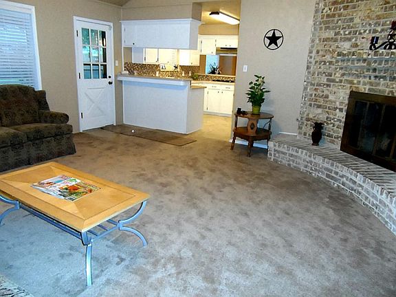Another angle of the living area that shows the kitchen and the back door that leads to the covered patio