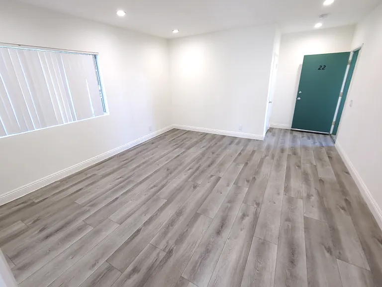 living room with nice open space, lighting, and a large window that overlooks the front entrance.