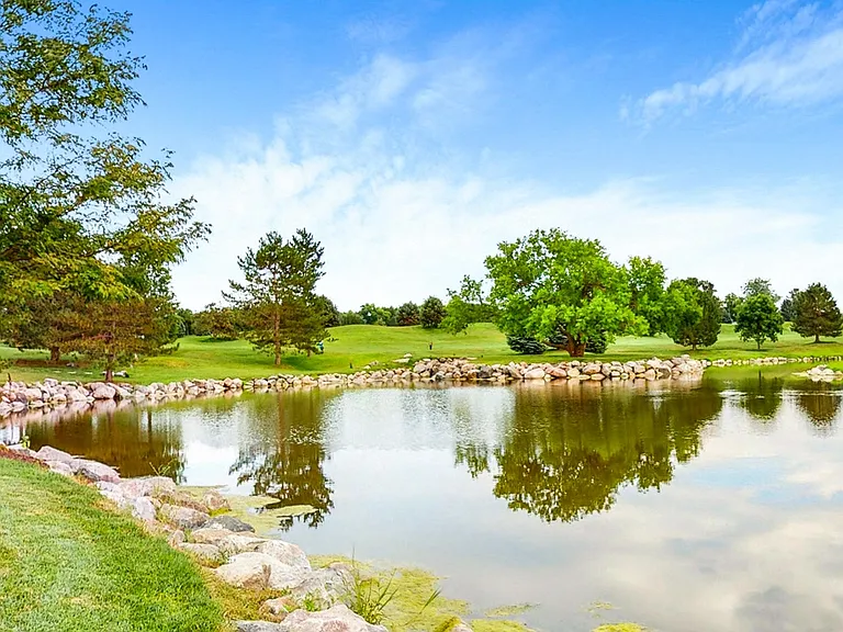 Find your moment of calm beside the sparkling pond, where lush greenery and open skies set the perfect scene for relaxation.