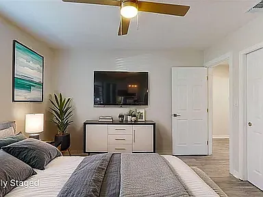 Stylishly furnished private bedroom with queen bed, full-length mirror, nightstands, and warm lighting