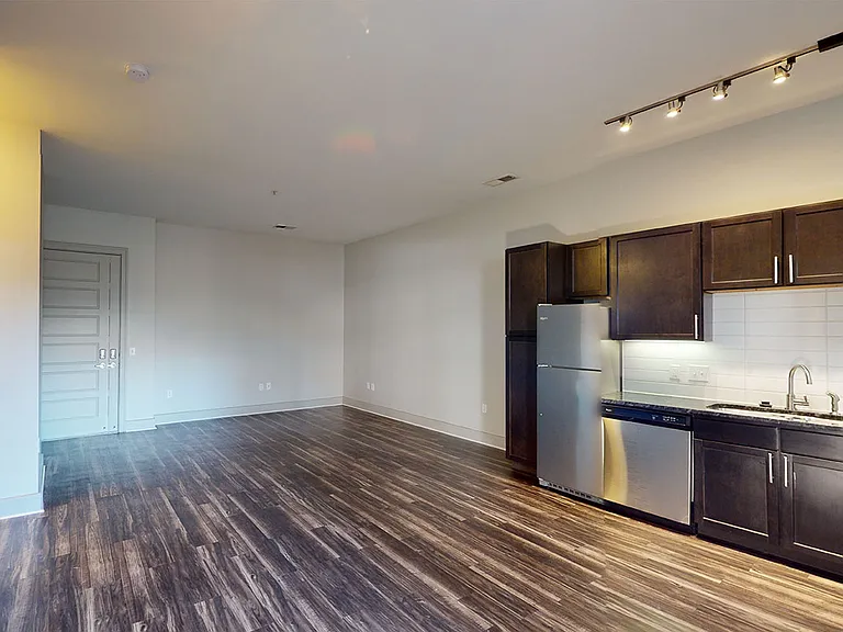Gourmet kitchen with stainless steel appliances, dining and living room with wood-style flooring.