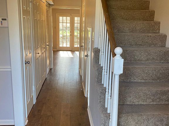 Entry hallway with coat closet, half bath, laundry, under stairs storage and living room in the distance