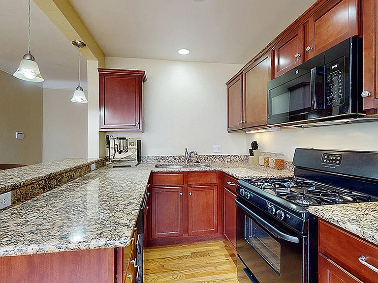 Elegant kitchen with granite countertops, cherry wood cabinets, and modern appliances, perfect for culinary enthusiasts.