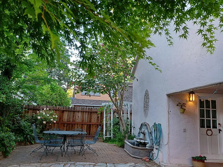 Secure backyard with fountain and outdoor seating amidst maple trees and roses