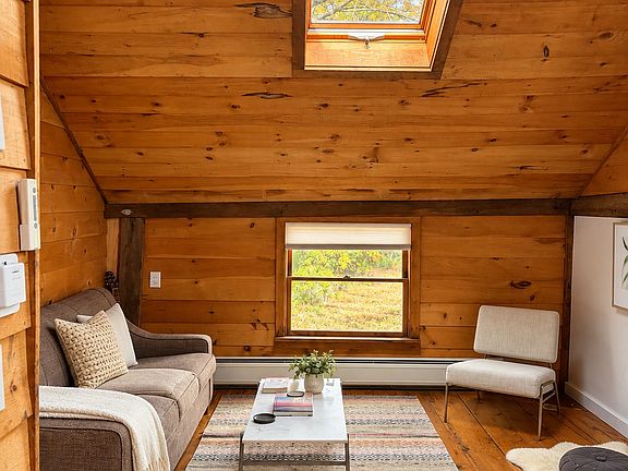 Soaring wood-clad ceilings, original wide-plank pine floors, and a dramatic skylight fill the inviting living space with historic character and natural light.