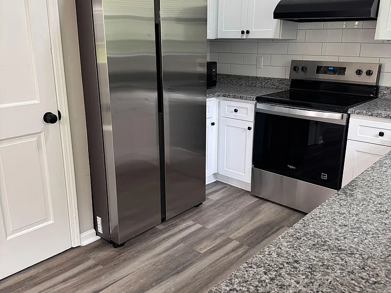 Updated kitchen with shaker cabinetry, granite-look counters, tile backsplash, and stainless steel fridge and range.