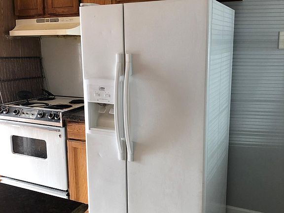 Galley kitchen with ceramic tile floors. Includes side by side refrigerator, stove, & dishwasher.