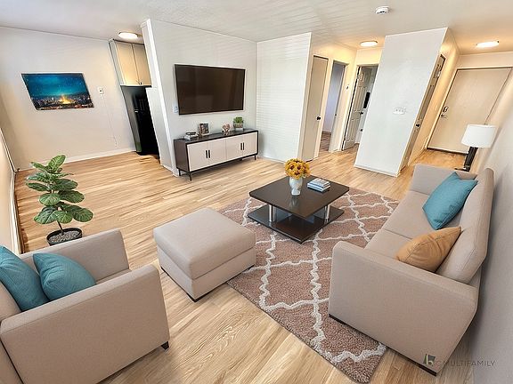 Inviting living room with stylish beige seating, modern decor, and a cozy ambiance highlighted by natural wood flooring and vibrant artwork.