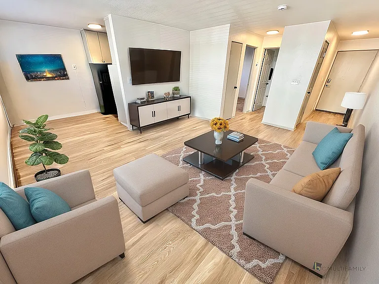 Inviting living room with stylish beige seating, modern decor, and a cozy ambiance highlighted by natural wood flooring and vibrant artwork.