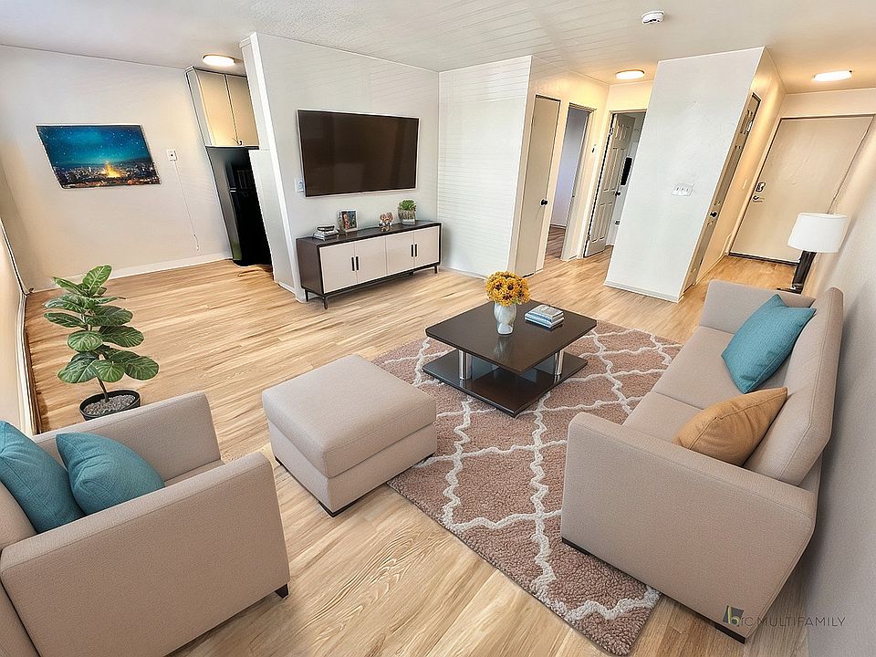 Inviting living room with stylish beige seating, modern decor, and a cozy ambiance highlighted by natural wood flooring and vibrant artwork.