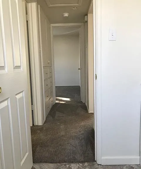 Hallway with second bedroom immediate to left. Living to right. Master bedroom in the distance. Storage space on left after 2nd bedroom entrance.