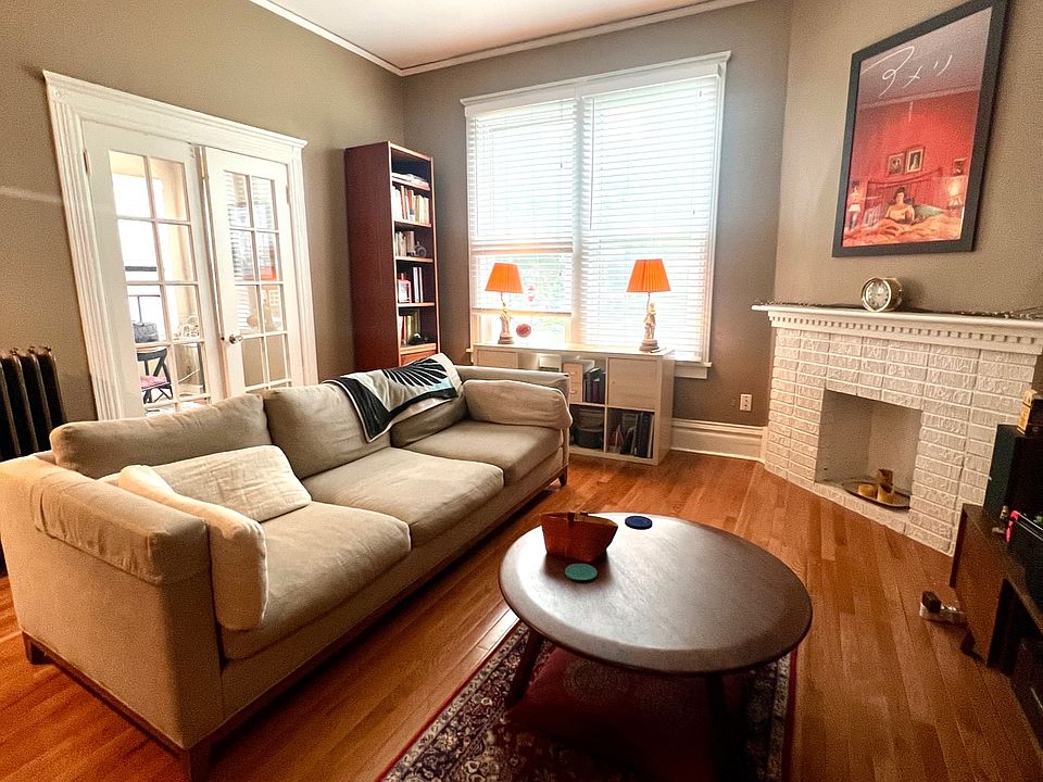 Large living room with 10 foot ceilings, oak hardwood floors, crown moldings, tall baseboards, and decorative fireplace