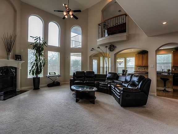 The game room upstairs looks down on the family room below with a picturesque Juliette balcony with iron balustrades. The open island kitchen & breakfast room are connected through the arched doorways. You can see the large covered patio upstairs.