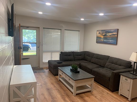 Living room includes stylish couch, console coffe table, side table, lamp, picture, television.