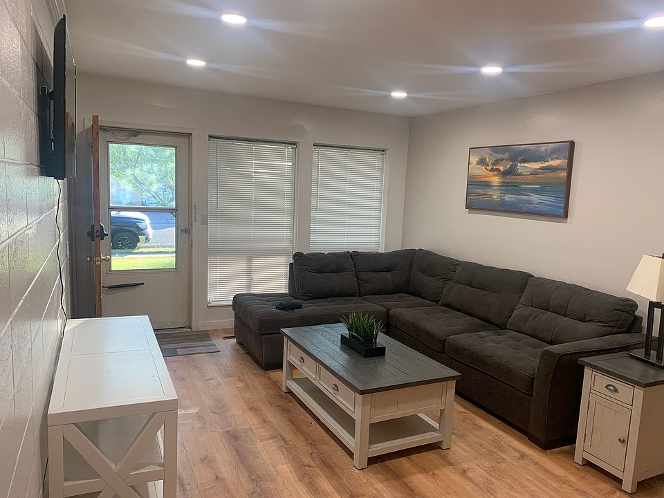 Living room includes stylish couch, console coffe table, side table, lamp, picture, television.