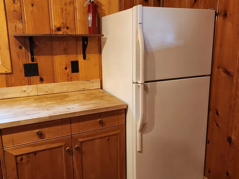 A Standard Size Refrigerator and Butcher Block Counters
