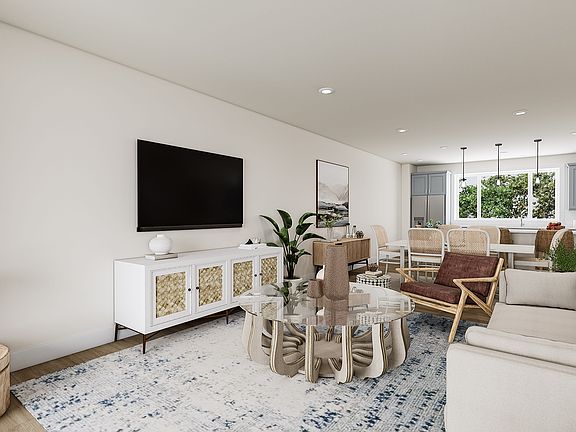 A cozy and well-furnished living room with a large TV, a wooden dining table, and a comfortable sofa