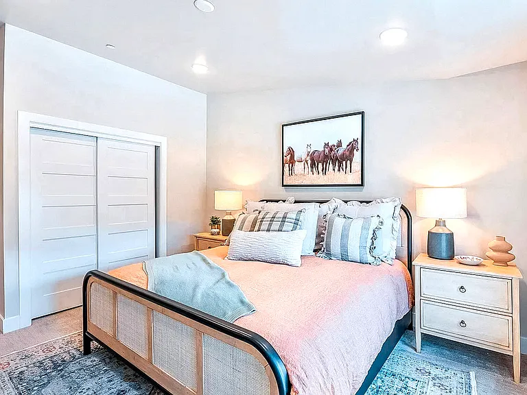 Cozy bedroom featuring a stylish cane headboard, soft bedding, and a blue patterned area rug
