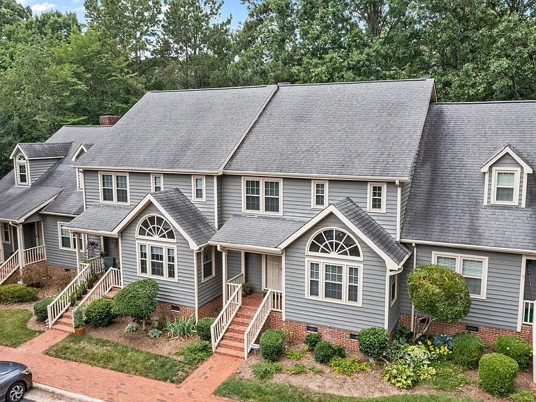 Elevated exterior view highlighting the townhome setting, brick walkways, and leafy surroundings.