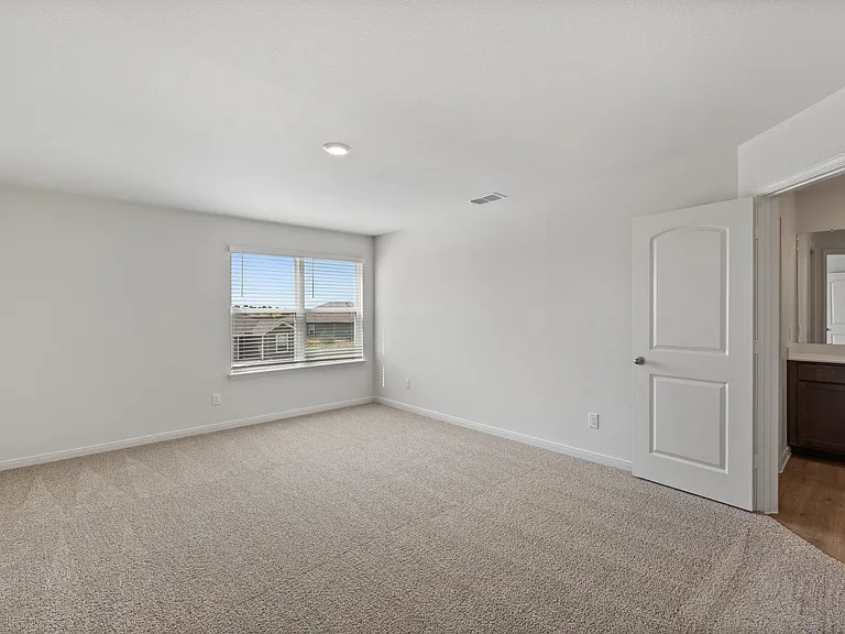 The spacious master bedroom has a large window that lets in natural light and backyard views.