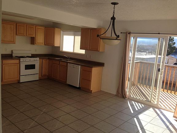 Kitchen/Dining area with sliding glass doors onto a small patio with stairs down to the large grassed back yard and extra garden space.