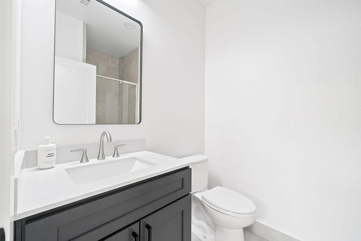 Clean bathroom with a wide vanity, undermount sink, and large mirror, plus a tiled shower for easy daily use. - Carver Ave
