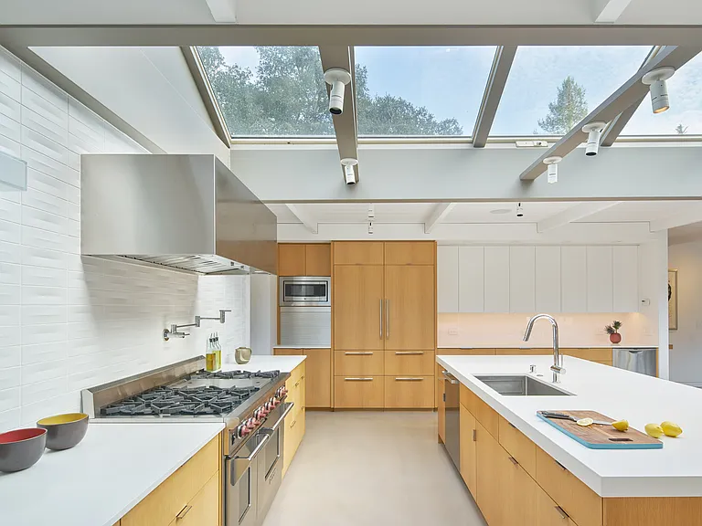 The fully equipped kitchen boasts top-of-the-line stainless steel appliances, silestone countertops, two dishwashers, a six burner Wolf range, and a large center island with comfortable counter seating for four.
