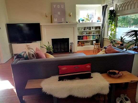 Large dining room has fireplace and built-in book case with lots of light for plants.