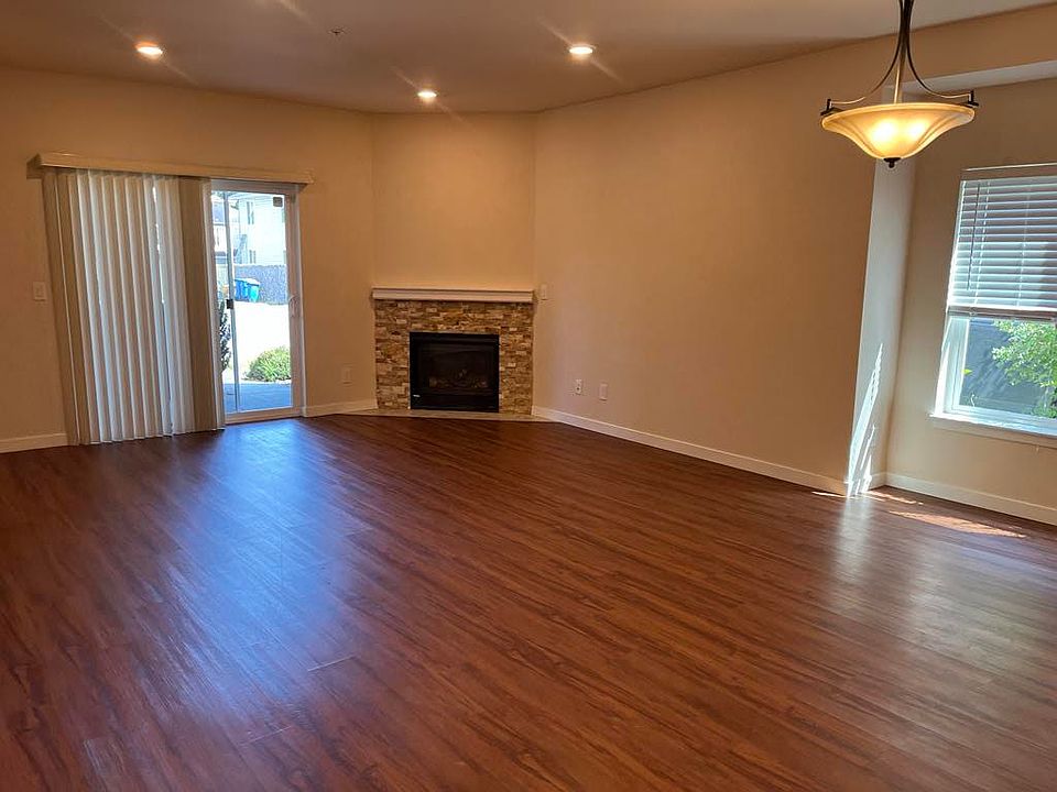 Spacious living and dining area with modern LVP flooring, elegant fireplace, and large windows and sliding door providing excellent natural light and easy outdoor access.