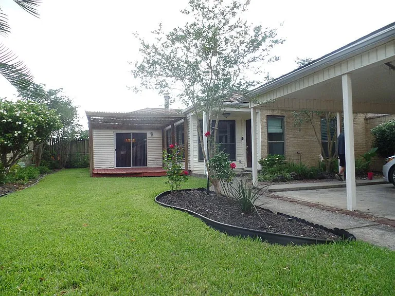 Nice patio is surrounded with a beautiful landscape and a two car carport.