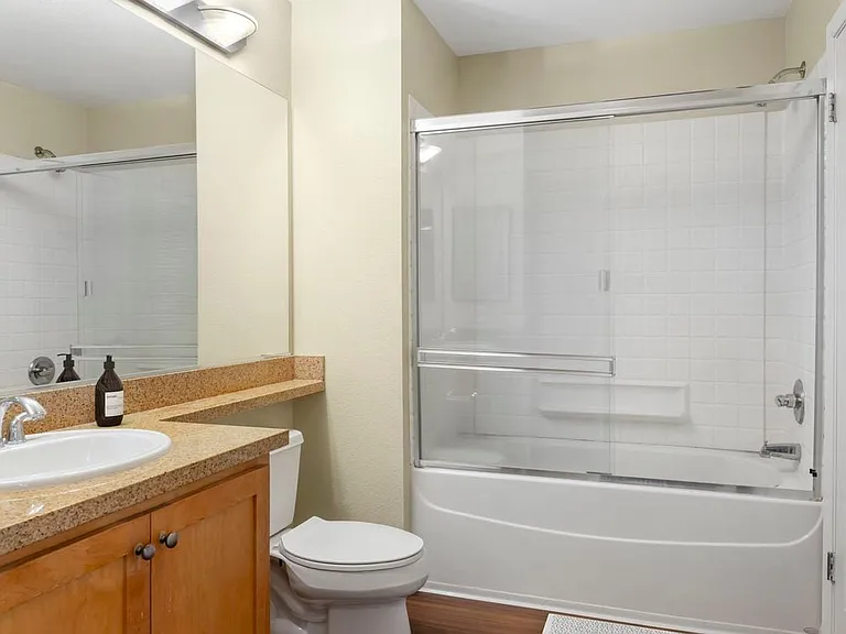 Classic Package II bath with oak cabinetry, beige speckled laminate countertops, and hard surface flooring