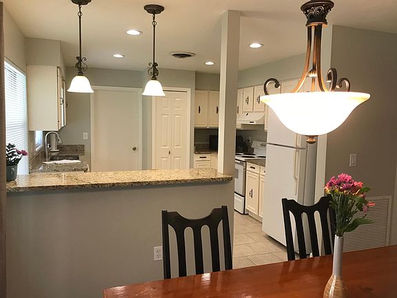 Large open kitchen and dining room with granite counters and 2 bar stools