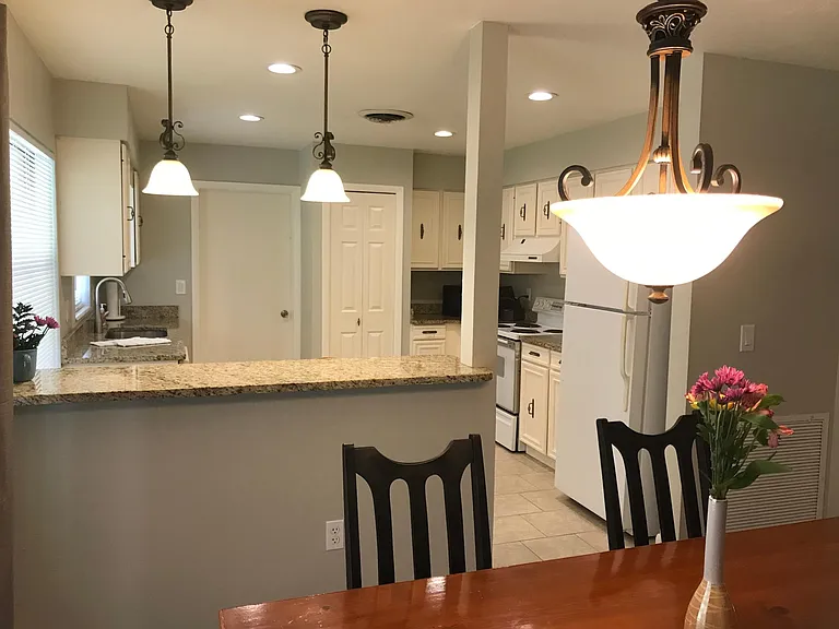 Large open kitchen and dining room with granite counters and 2 bar stools