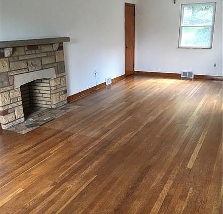 Living room boast beautiful hardwood floors with a stone decorative fireplace that leads into the sun room.