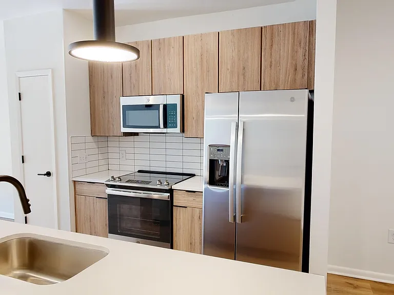 Apartment Kitchen with Stainless Steel Appliances, Quartz counter tops and Wood Style Flooring.