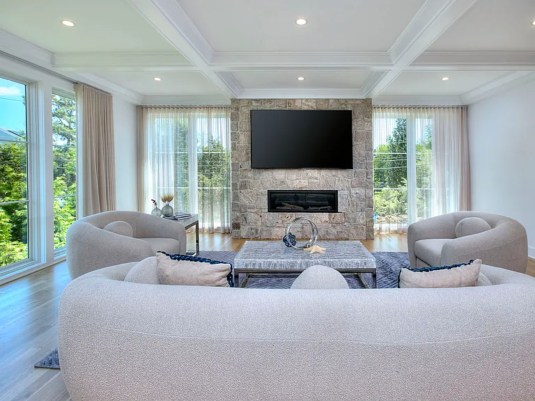 Living room with gas fireplace, coffered ceiling, floor length curtains for privacy, and direct water views of the sound.