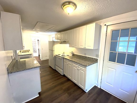 View from the eat-in area of kitchen. Note the stove and refrigerator included. Laundry room and storage to the right and attic storage accessed from pull down stairs.