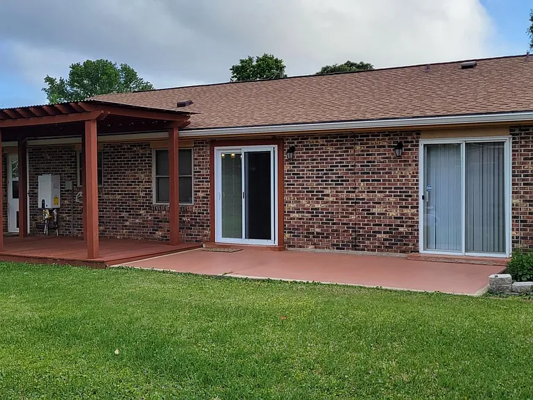 The fenced back yard has a covered deck, patio and lush grass.