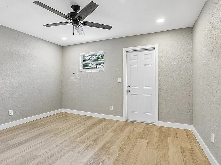 Bright, modern room with sleek wood flooring, neutral walls, and elegant ceiling fan, perfect for customization.