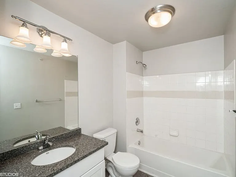 White tiled bathroom with overhead and mirror lighting