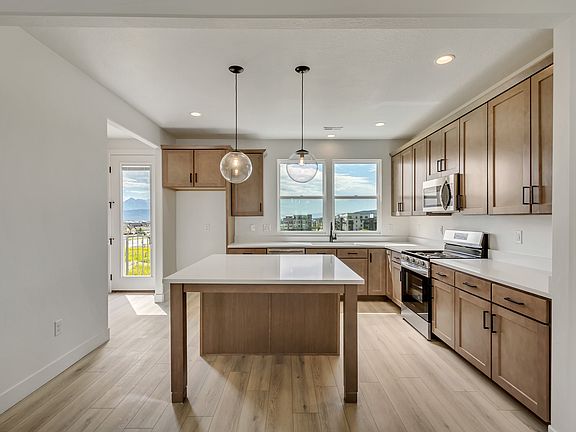 Modern kitchen with wooden cabinets, island counter, stainless steel appliances, two pendant lights,