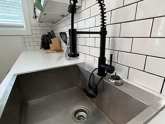 Deep, stainless steel kitchen sink, with matt black telescoping multi-spray faucet.