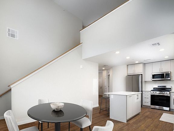 Loft apartment with stainless steel appliances, white quartz countertops, light grey cabinetry, and hard surface flooring