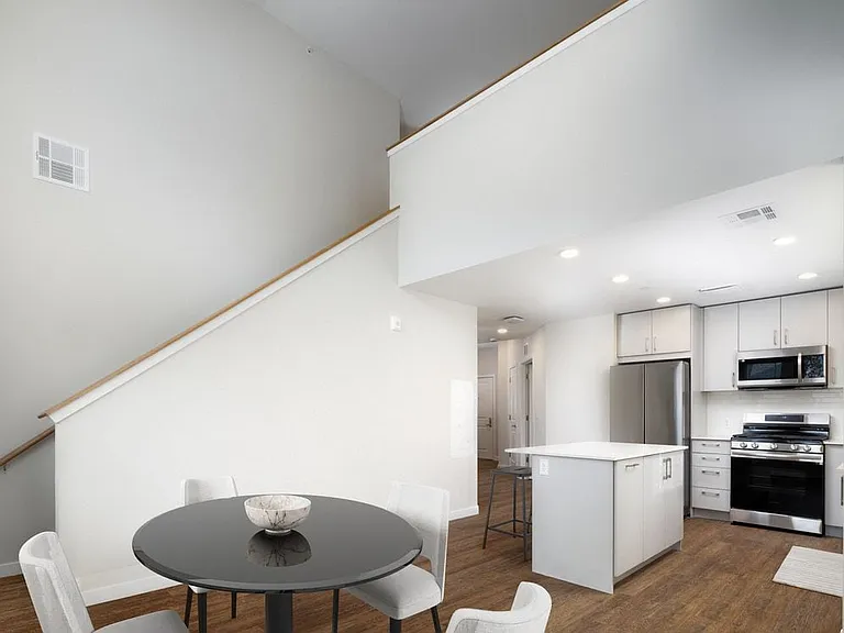 Loft apartment with stainless steel appliances, white quartz countertops, light grey cabinetry, and hard surface flooring