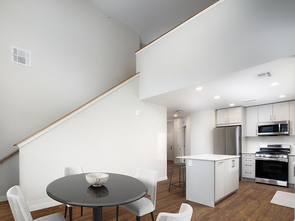 Loft apartment with stainless steel appliances, white quartz countertops, light grey cabinetry, and hard surface flooring